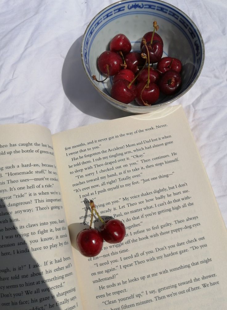 a bowl of cherries sitting on top of an open book