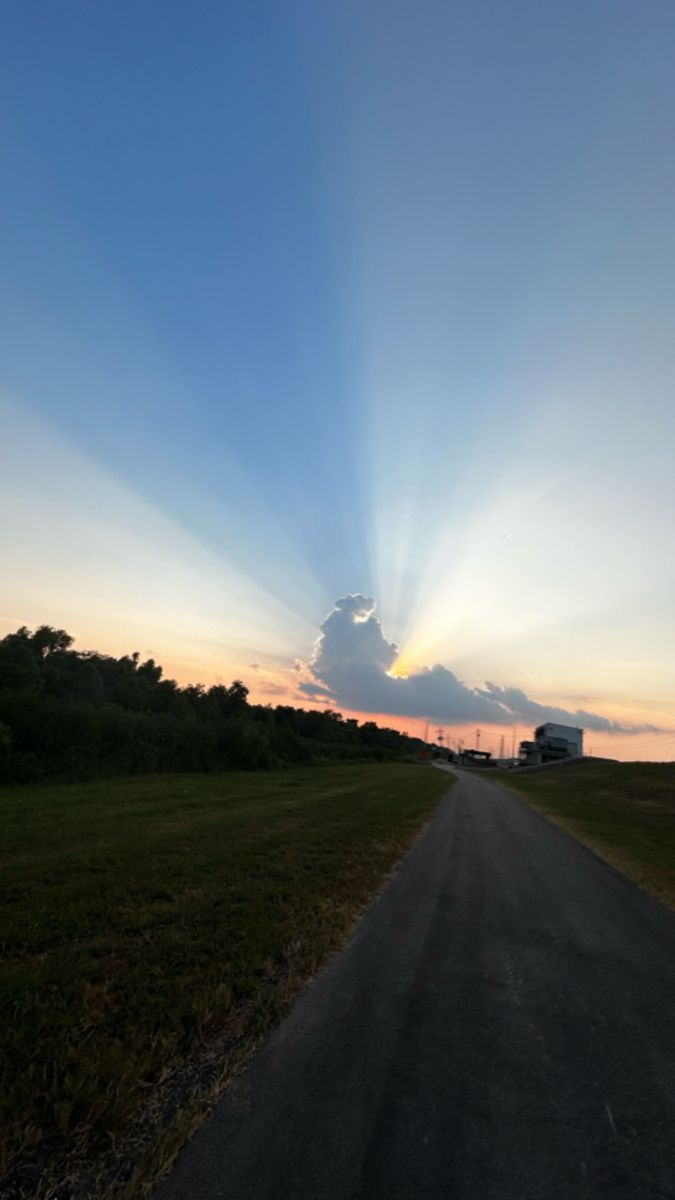 the sun is setting over an empty road