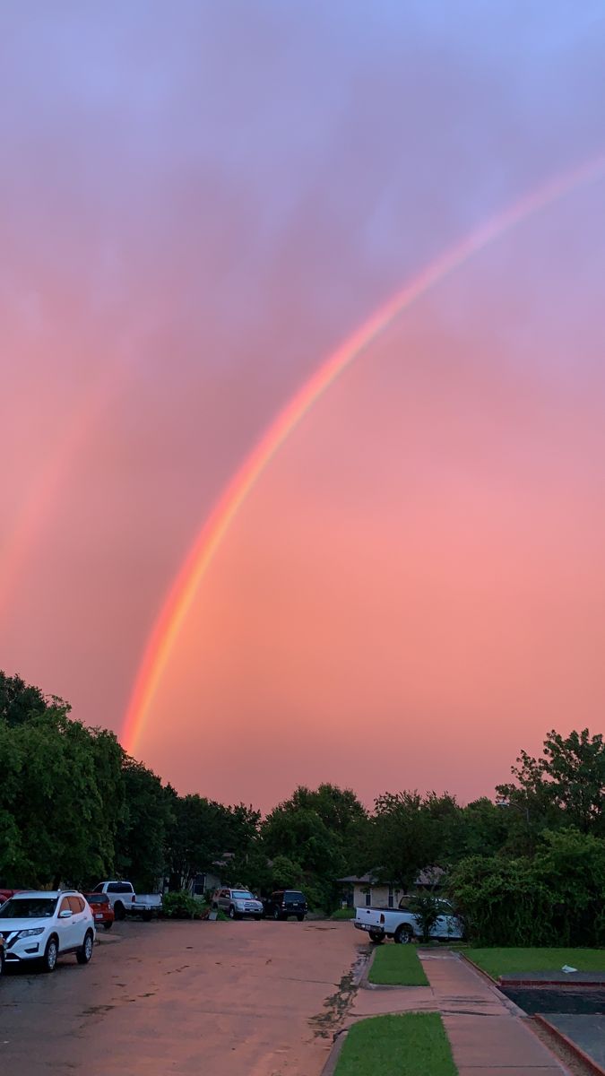 a rainbow in the sky over a parking lot