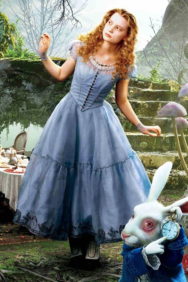 a woman in a blue dress standing next to a rabbit