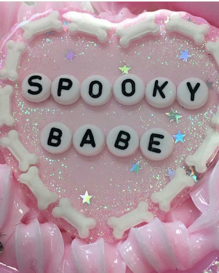 a pink heart shaped cake with the words spooky babe spelled in white frosting