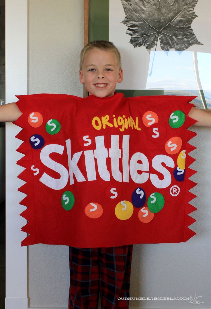 a young boy holding up a red skittles shirt