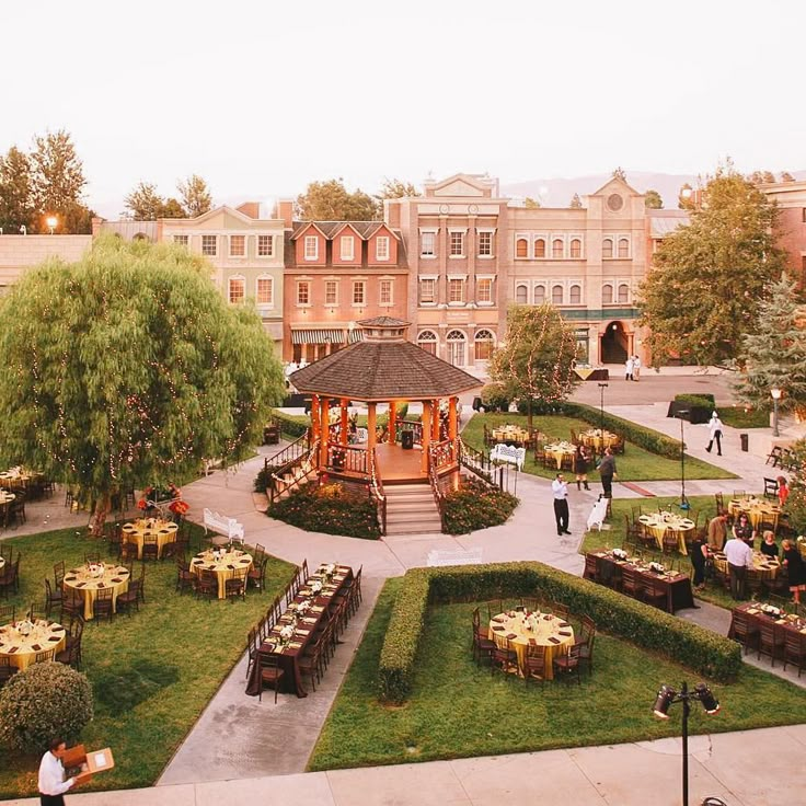 an outdoor dining area with tables and chairs in the center, surrounded by greenery