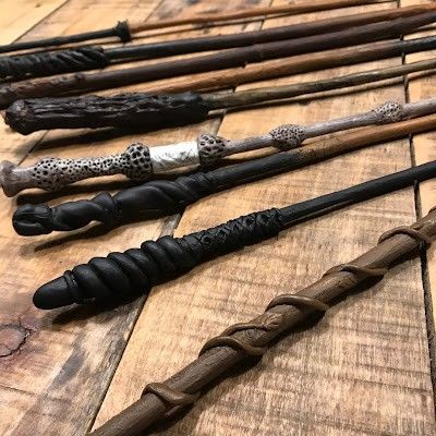 several harry potter wands lined up on a wooden table with black and white handles