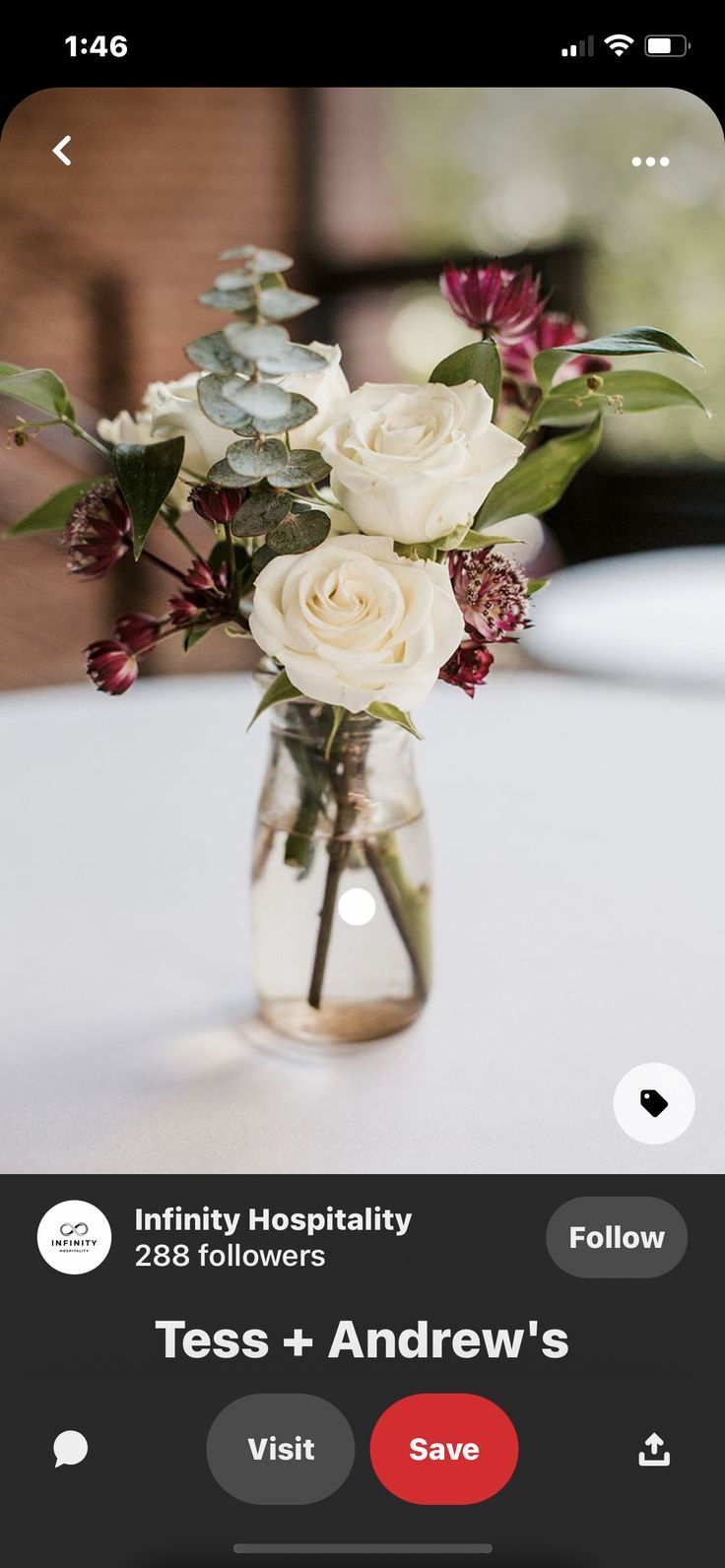 a vase filled with white flowers on top of a table next to a cell phone