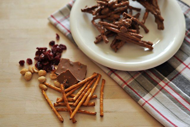 a plate with crackers, nuts and chocolate on it next to a dish towel