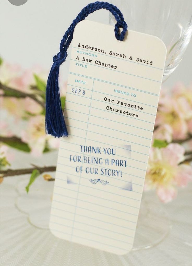 a bookmark with a blue tassel hanging from it's side next to flowers