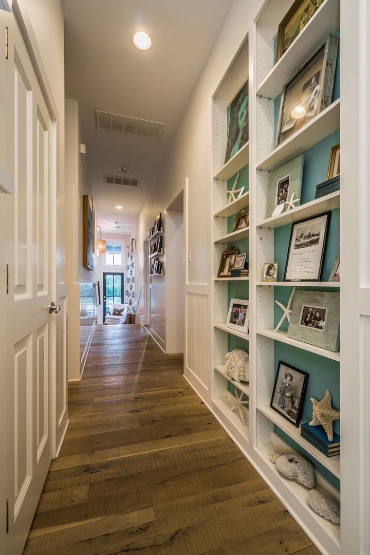 a long hallway with bookshelves and pictures on the wall in front of it