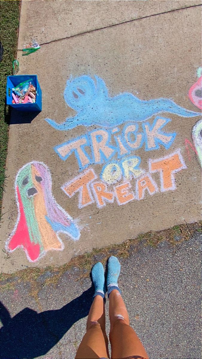 someone is standing on the sidewalk with their feet propped up in front of chalk drawings