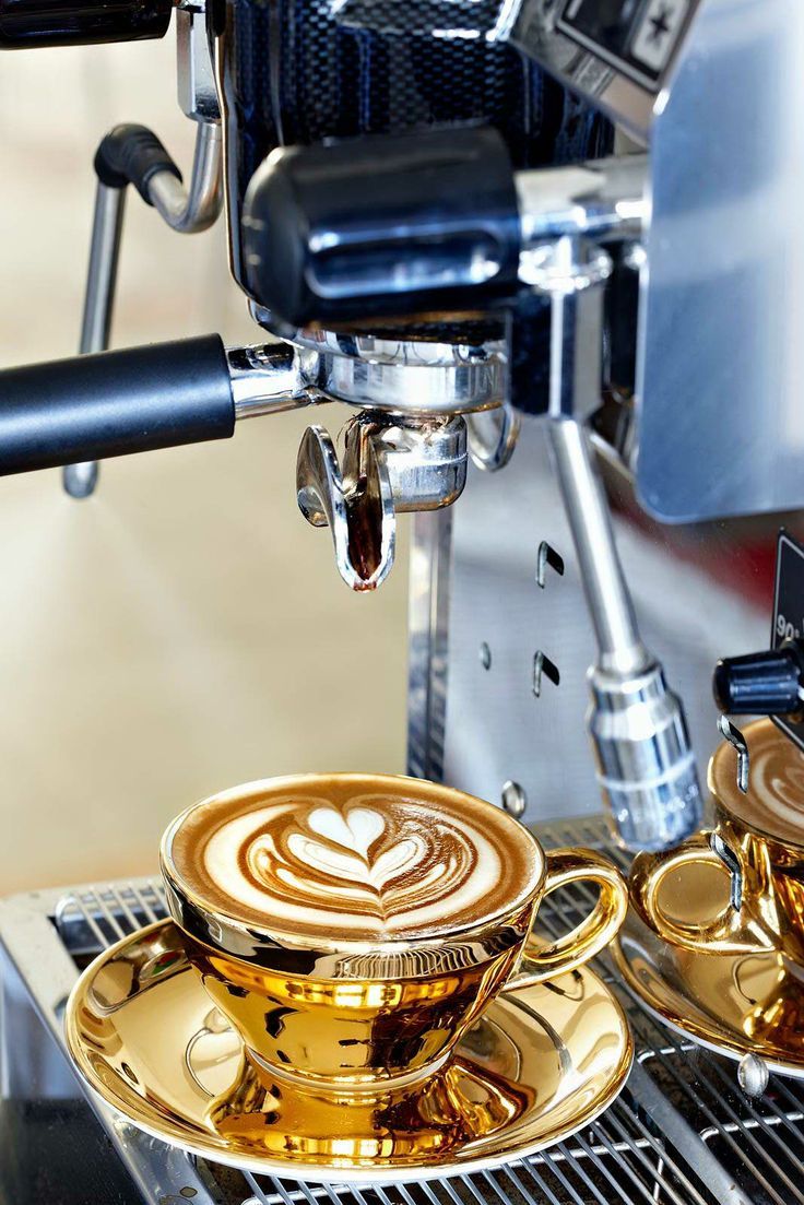 two golden coffee cups sitting next to each other on top of a saucer and stove