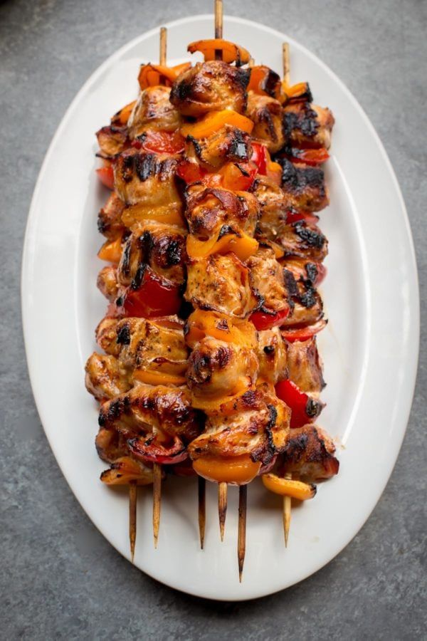 several skewers of meat and vegetables on a white plate