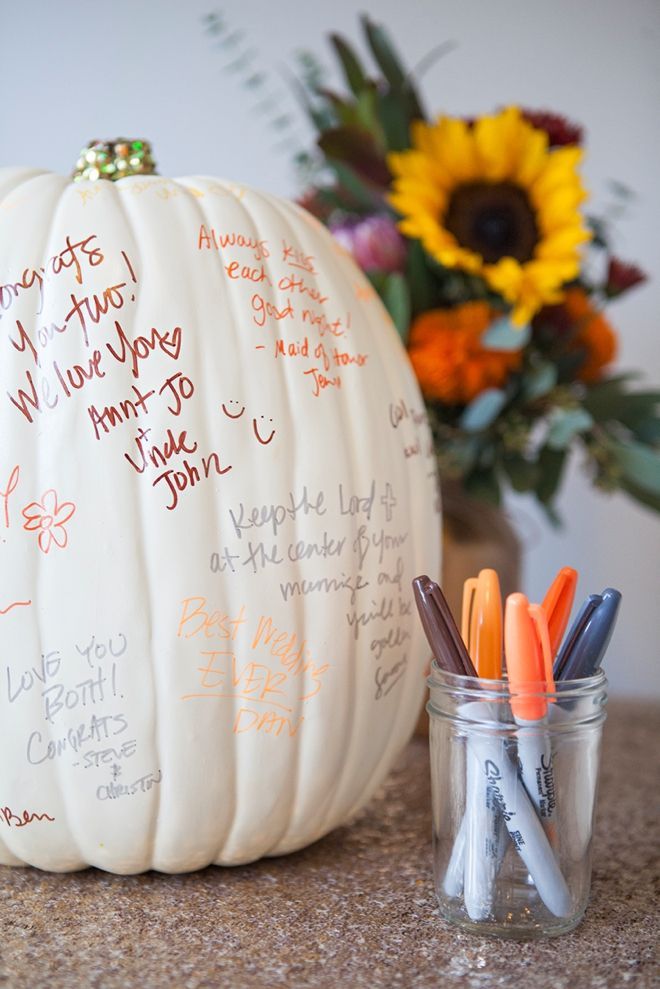 a white pumpkin sitting on top of a table next to a jar filled with markers