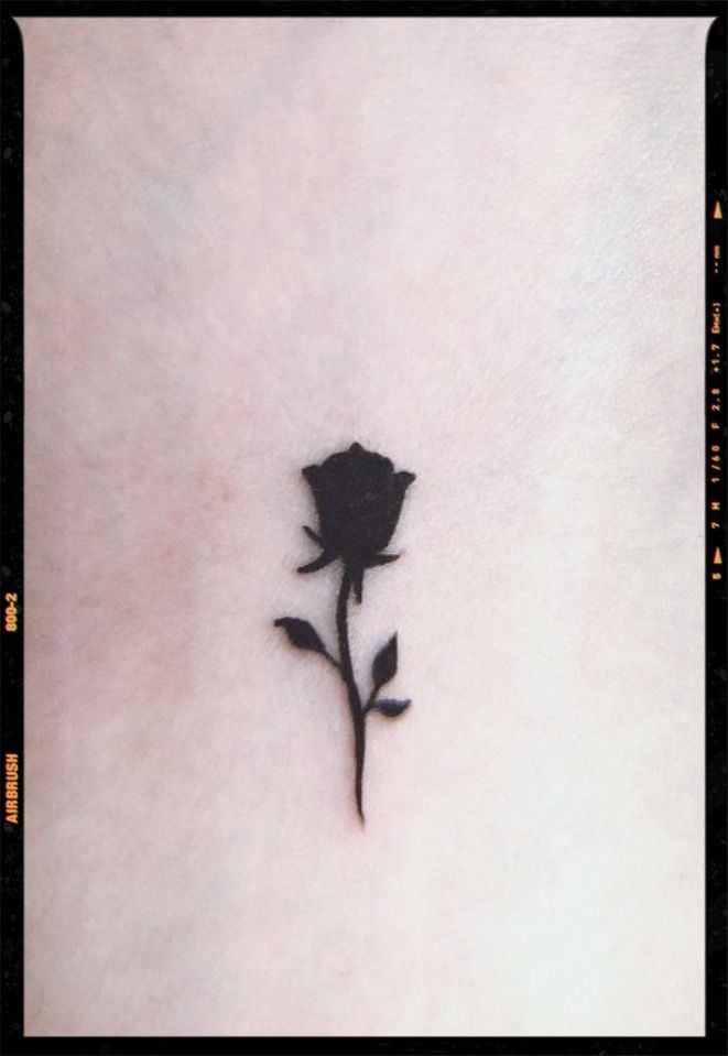 a small black rose tattoo on the back of a woman's stomach