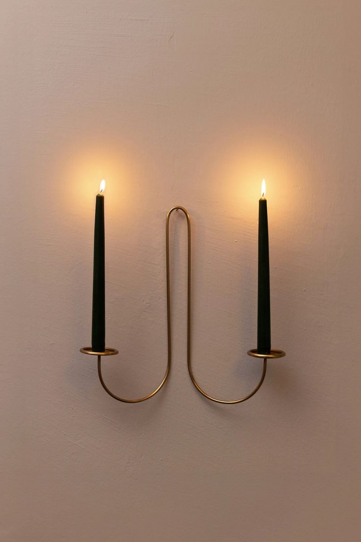 two candles are lit on the wall in front of each other, one is black