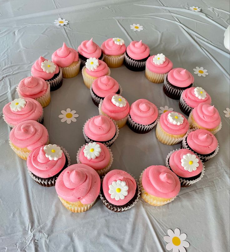 cupcakes with pink frosting and white flowers arranged in the shape of a circle