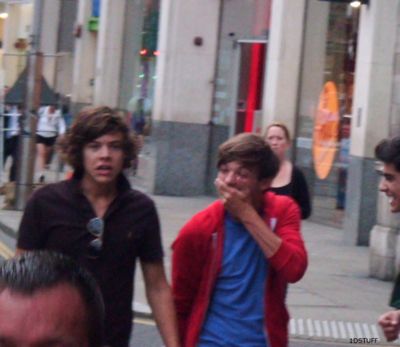 three young men walking down the street with one covering his mouth while another man looks on