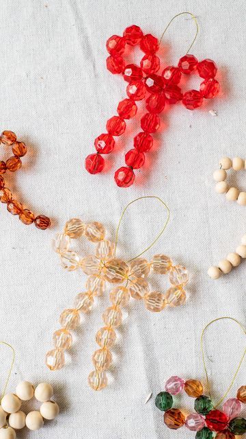 four beaded ornaments are arranged on a white tablecloth with red, yellow and green beads