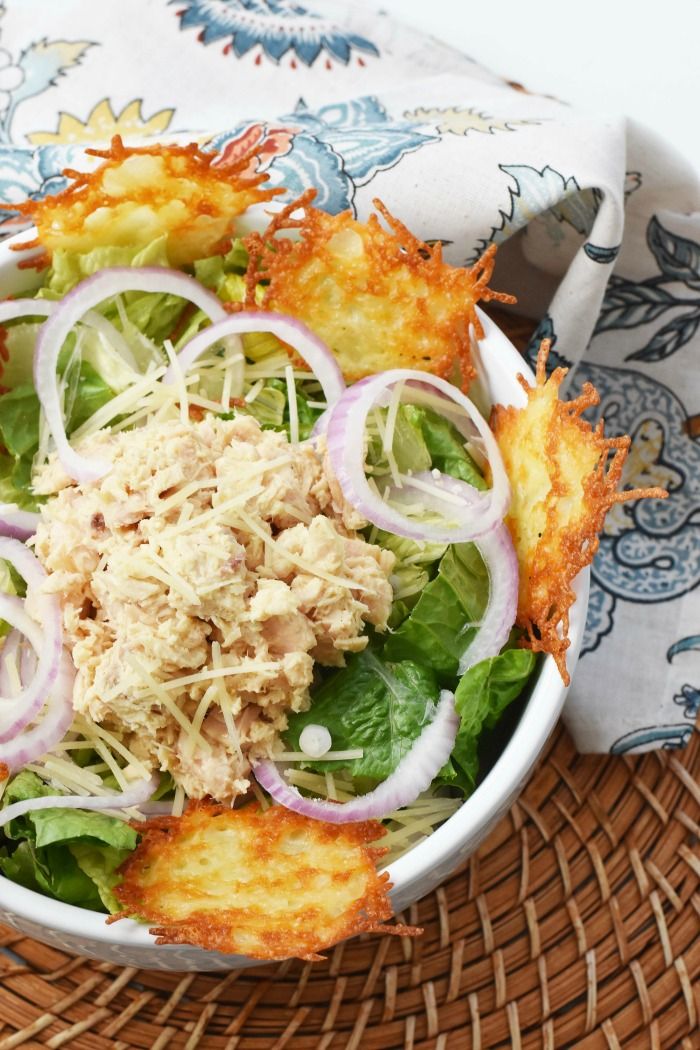 a white bowl filled with food on top of a woven table cloth next to a basket