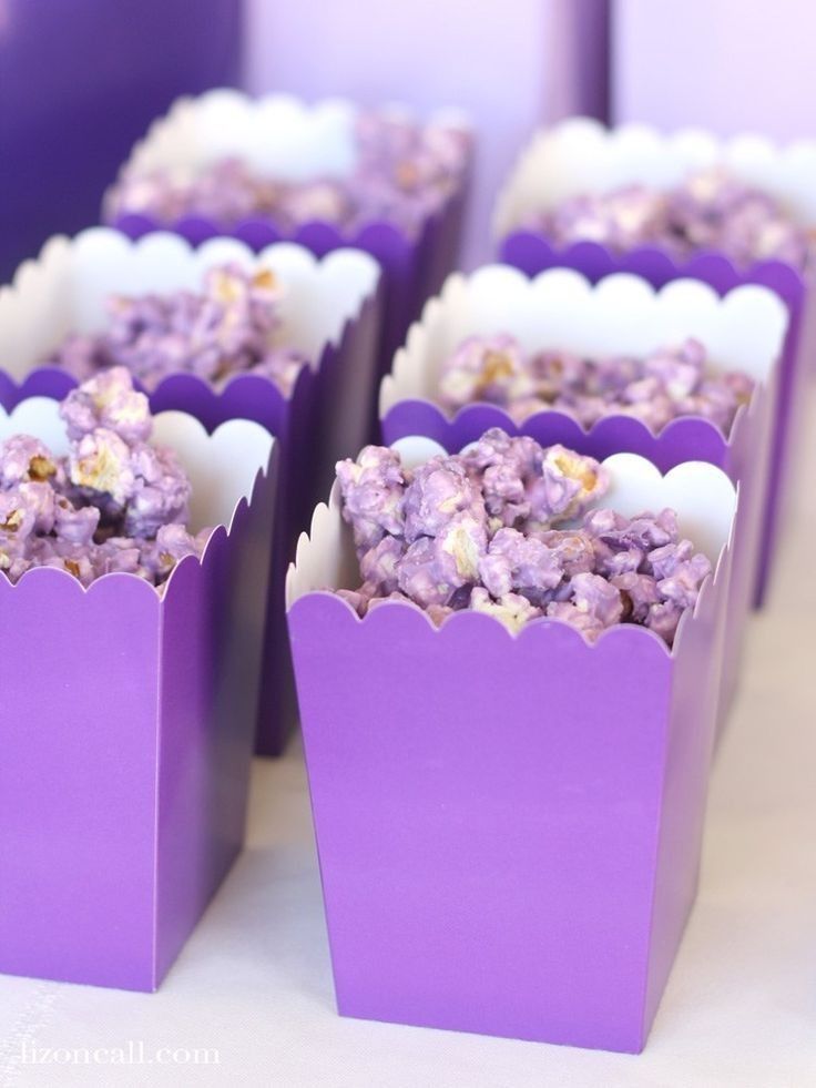 purple paper bags filled with popcorn sitting on top of a table