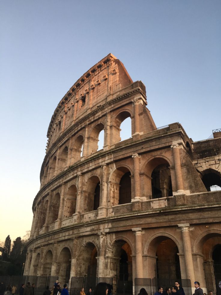 people are walking around in front of the roman collise at sunset or dawn