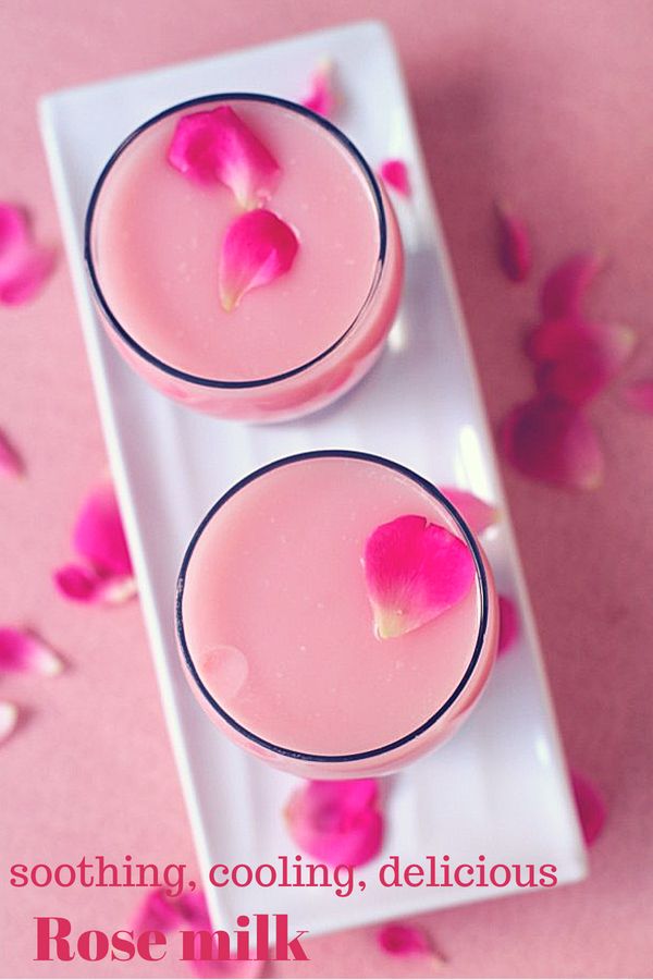 two glasses filled with pink liquid sitting on top of a white plate next to rose petals