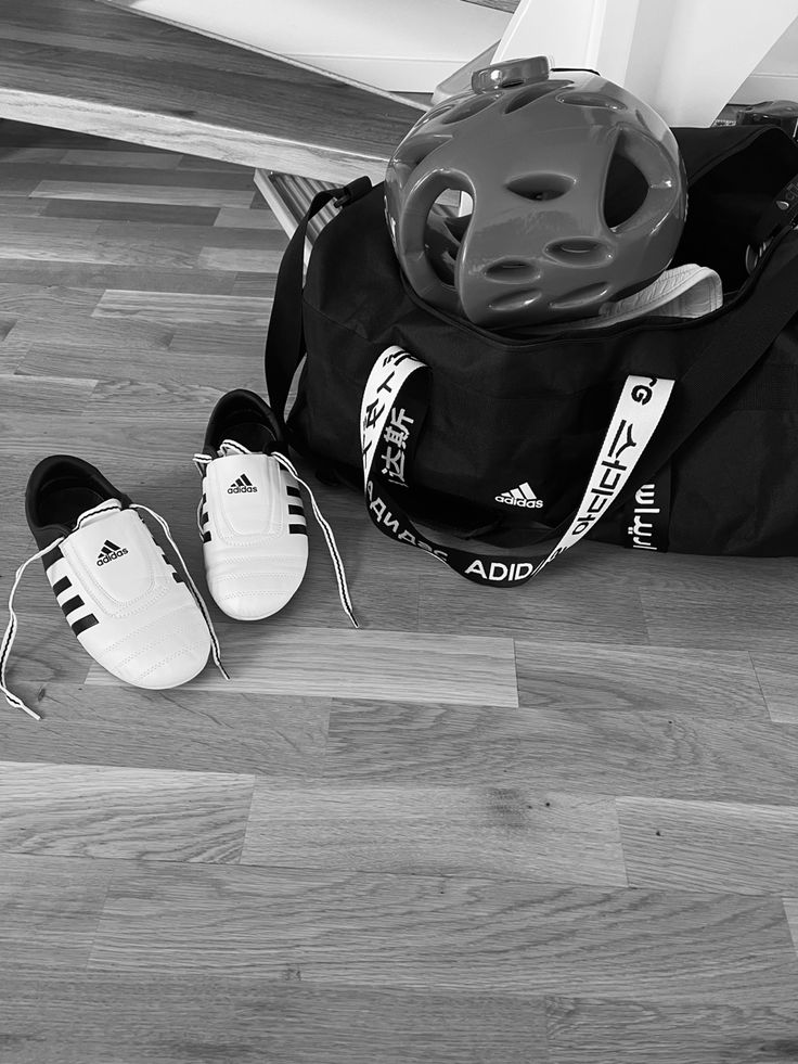 black and white photograph of sports equipment on the floor with shoes next to it,