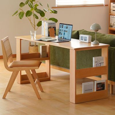 a laptop computer sitting on top of a wooden desk next to a green couch in a living room