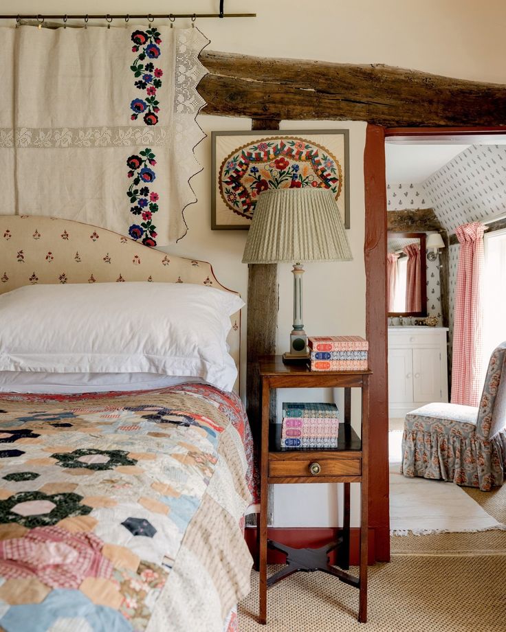 a bed sitting next to a wooden table with a lamp on it's side