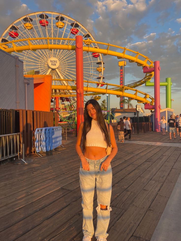 a woman standing on top of a wooden floor next to a ferris wheel at an amusement park