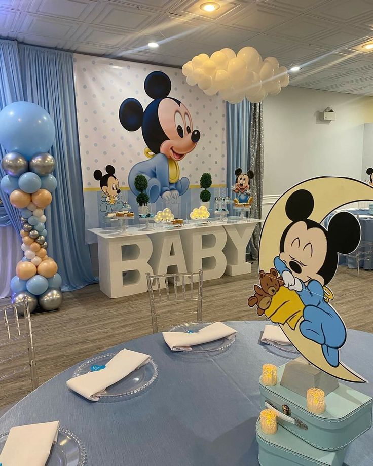 a mickey mouse themed baby shower with balloons and decorations on the walls, including a cake table