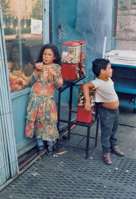 two young children standing in front of a store with their hands on the door handles