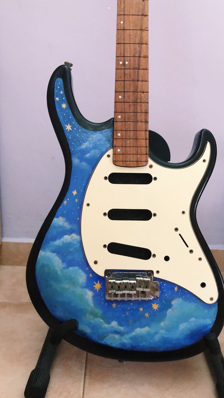 a blue and white electric guitar with stars on it's body sitting on a stand