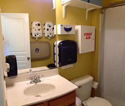 a bathroom with yellow walls and white fixtures, including a sink, toilet, and shower