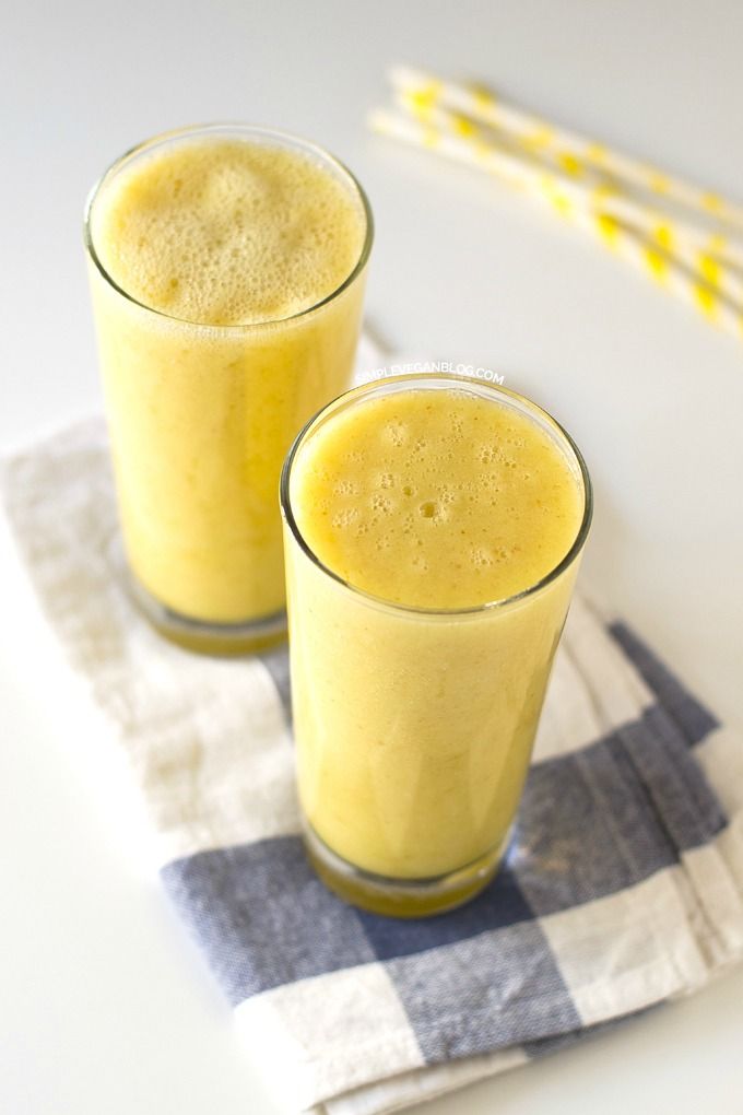 two glasses filled with yellow liquid sitting on top of a checkered napkin