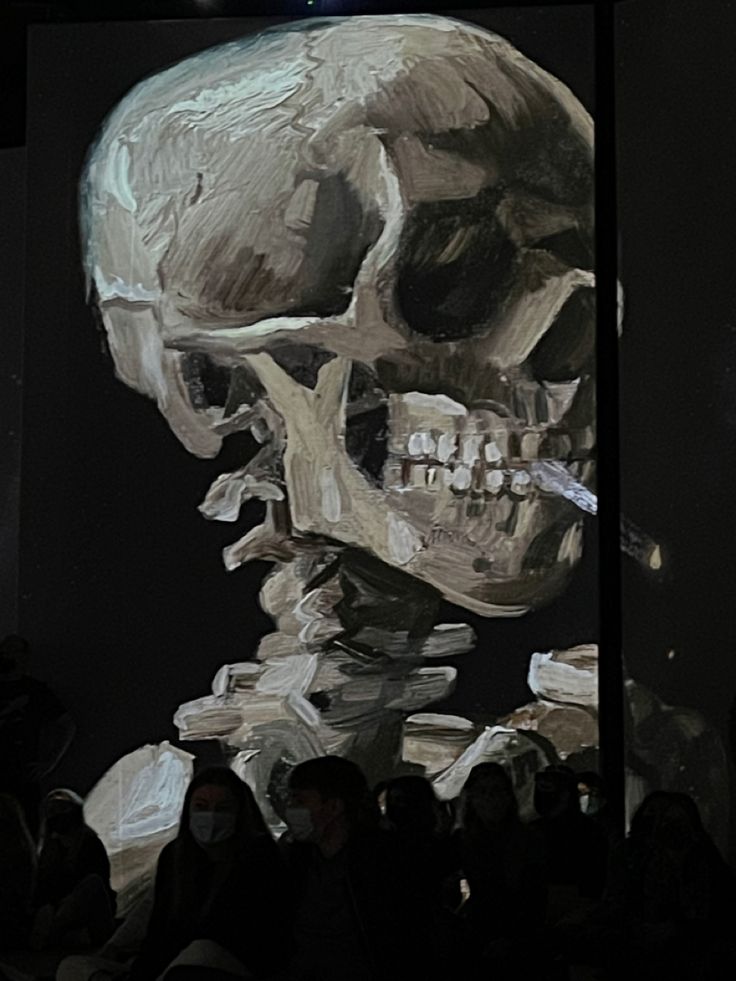 a painting of a human skull on display with people looking at it in the background