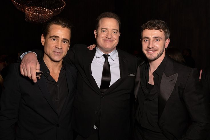 three men in suits posing for the camera