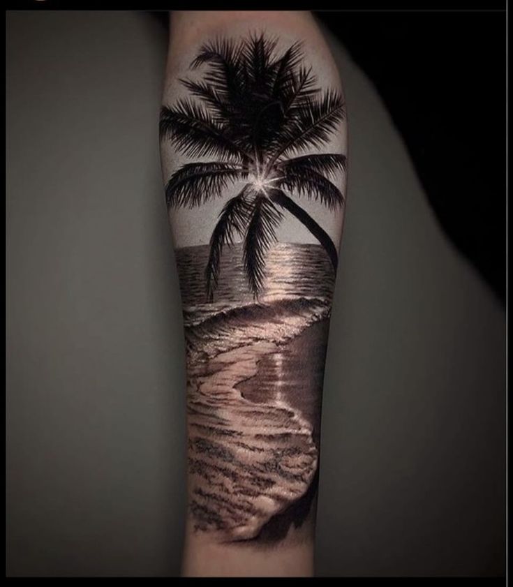 a man's arm with a palm tree on the beach and waves coming in