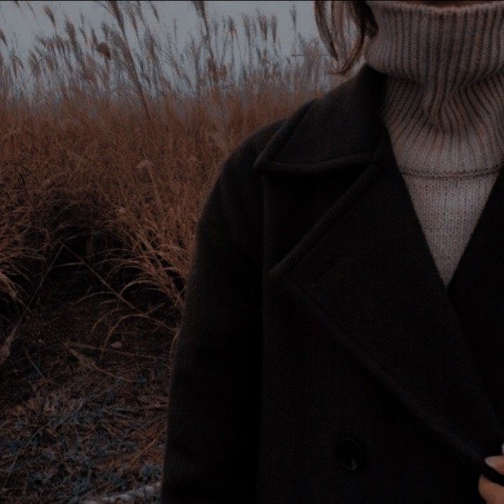 a woman in a black coat is holding a cell phone