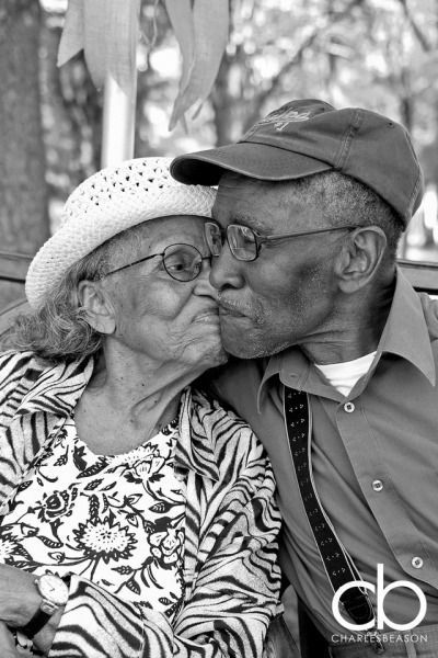 an older couple kissing each other while sitting on a bench