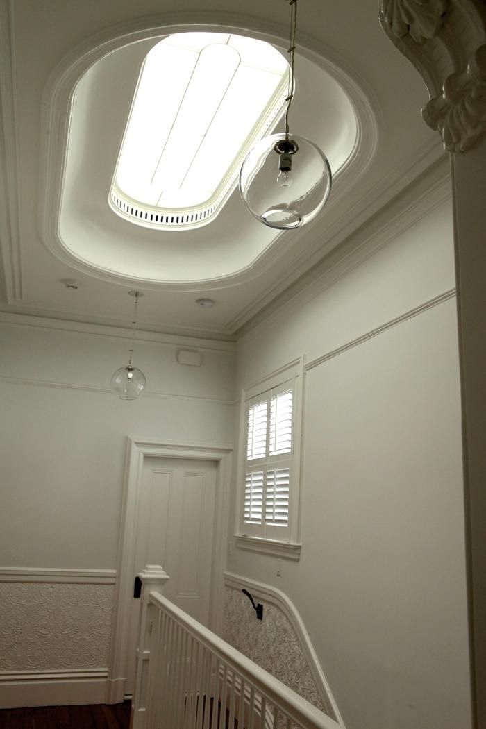 an empty white room with a skylight above the door and stairs leading up to it