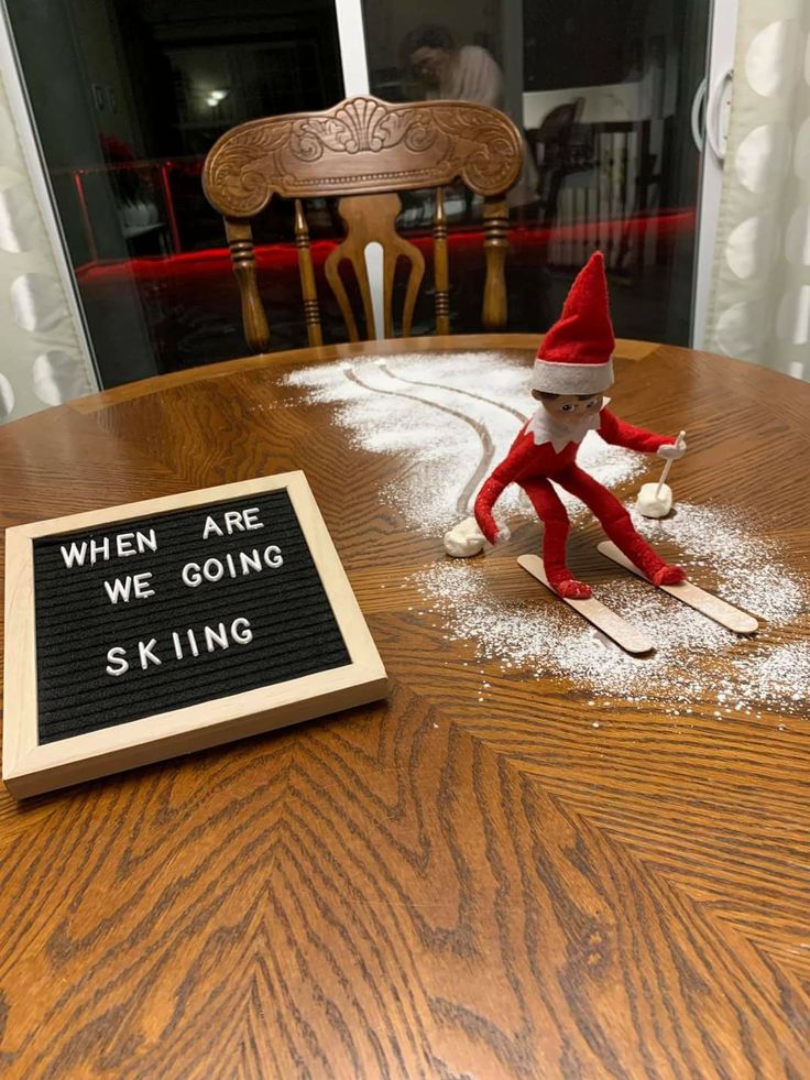 an elf on skis sitting in front of a sign that says when are we going skiing