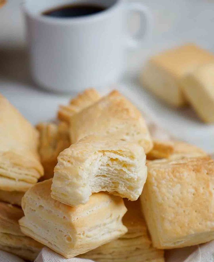 a pile of biscuits sitting on top of a table next to a cup of coffee