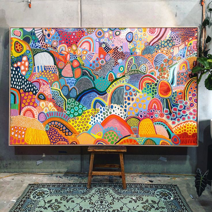 a large colorful painting on display in a room with rugs and potted plants