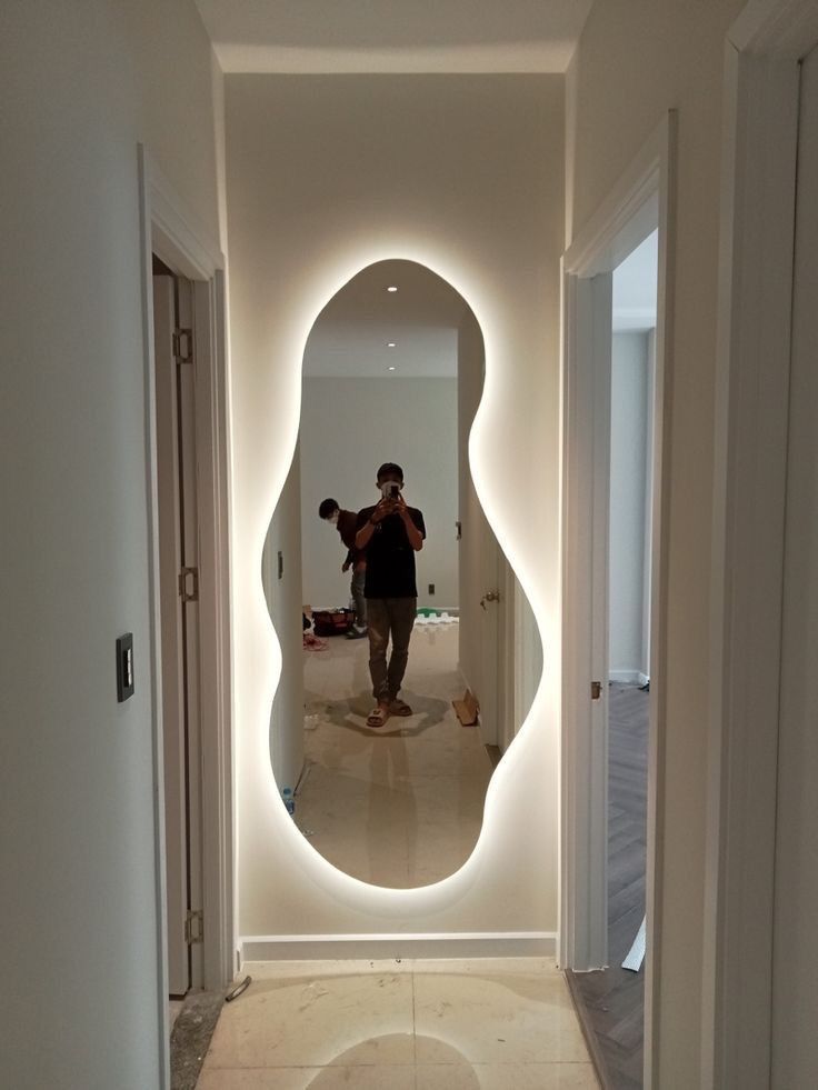 a man is taking a photo in the reflection of a large mirror on the wall