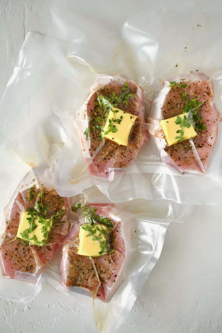 four pieces of meat wrapped in plastic and topped with cheese, herbs and parsley