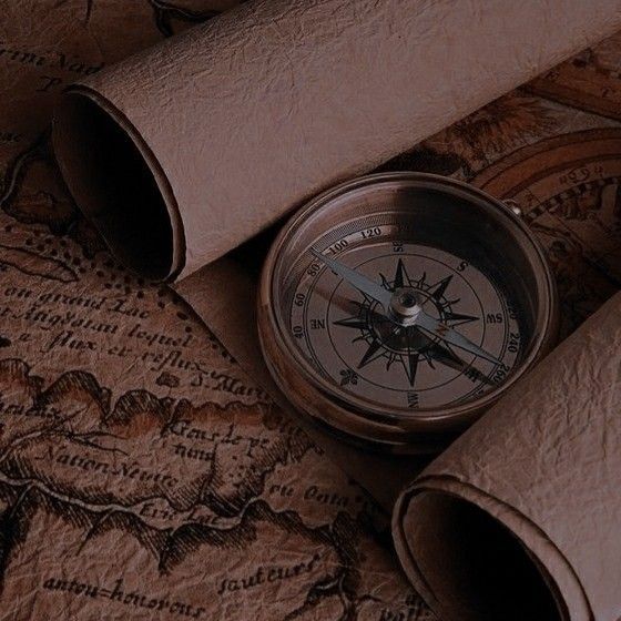 a compass is laying on top of a map and some rolled up leathers next to it