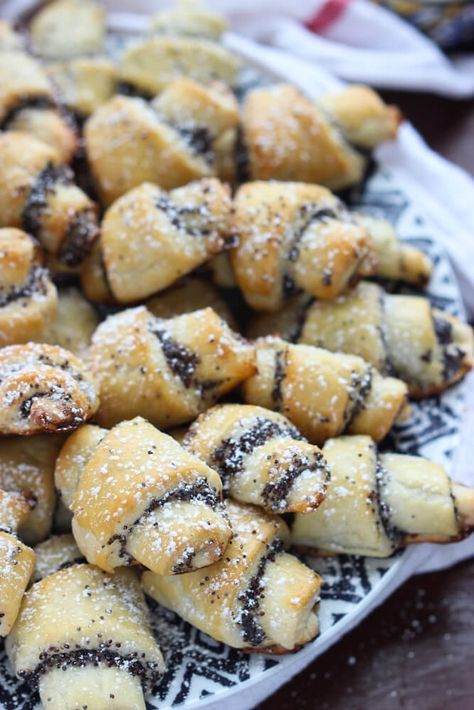 a white plate topped with lots of pastries on top of a wooden table covered in powdered sugar