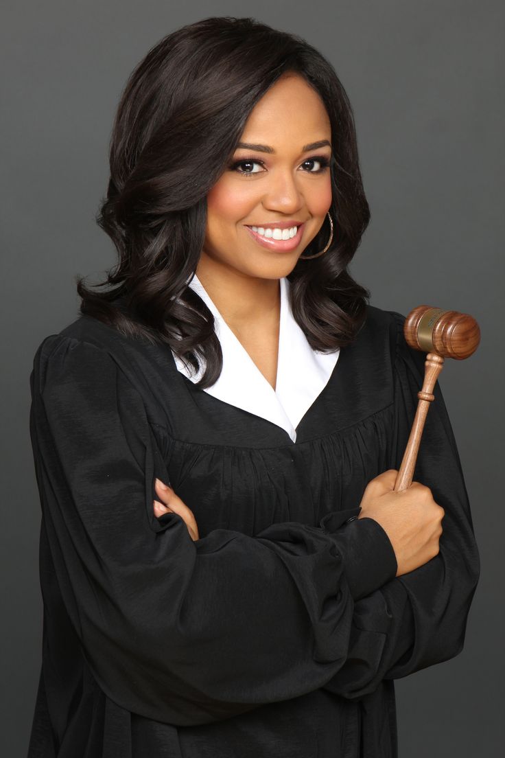 a woman in a black robe holding a wooden gavel and smiling at the camera