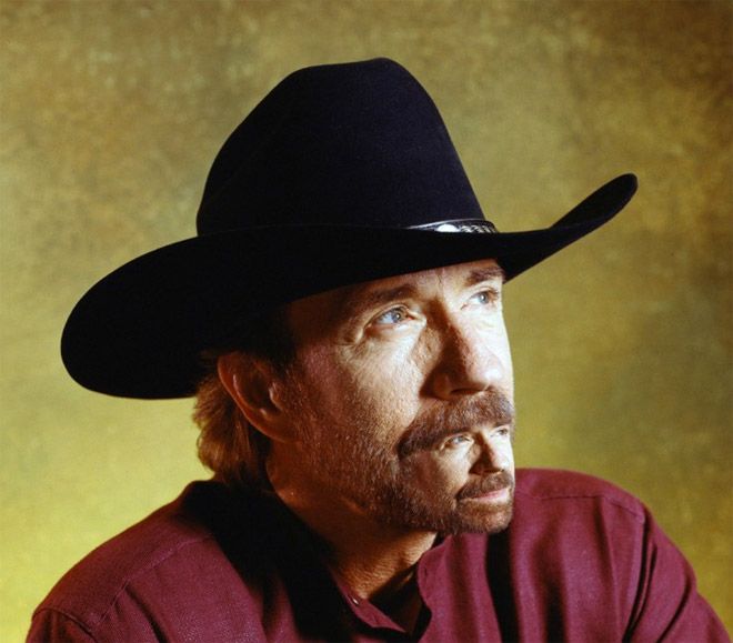 a man wearing a black cowboy hat looking off to the side with his hand on his hip