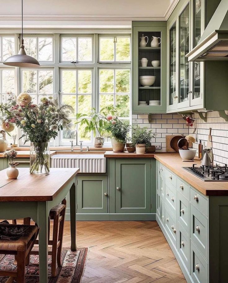 a kitchen filled with lots of green cupboards and counter top next to a window